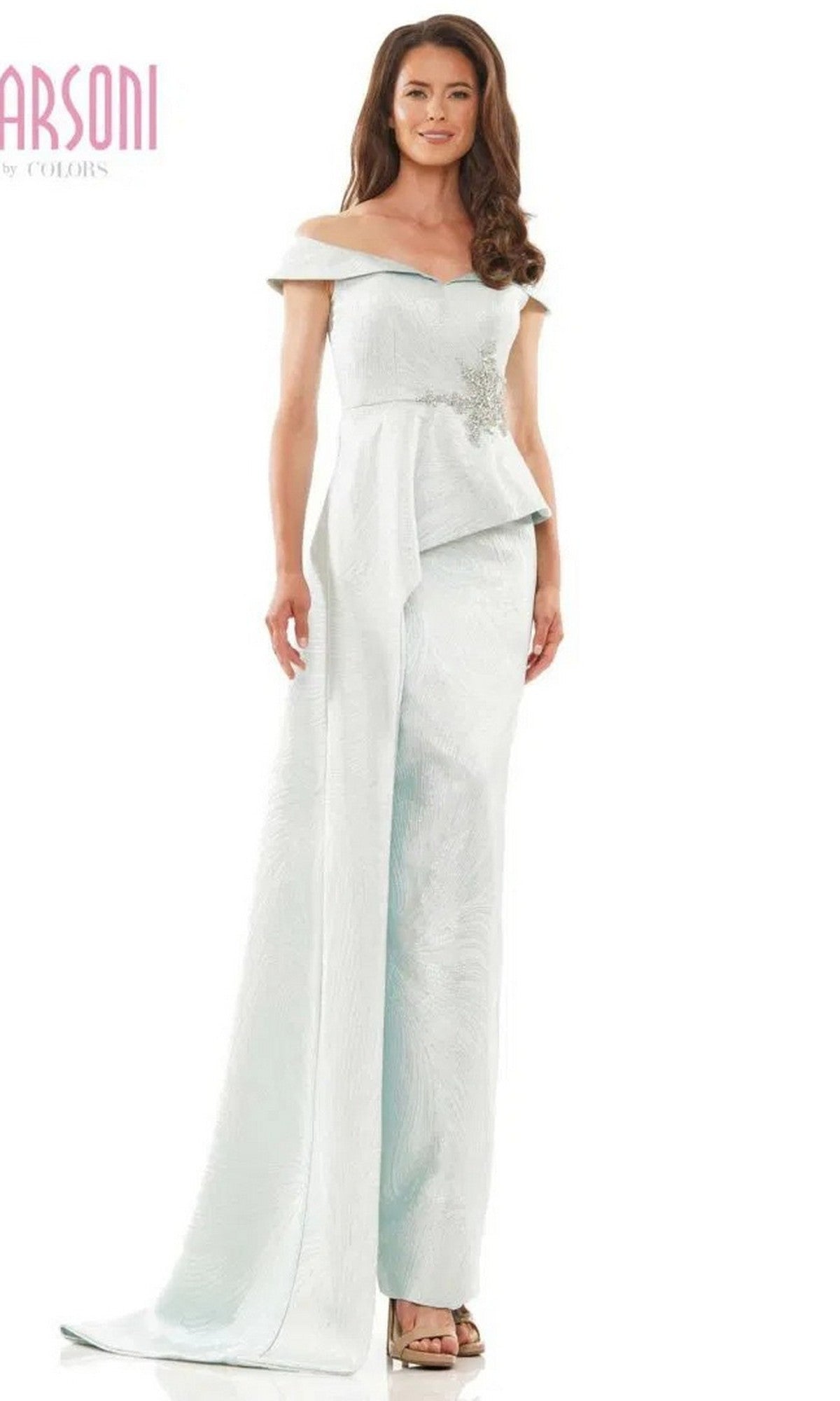 A woman wears the Marsoni MV1225 long formal dress in Seaglass, featuring an off-the-shoulder design, peplum waist, and wide-leg pants, standing against a white background.